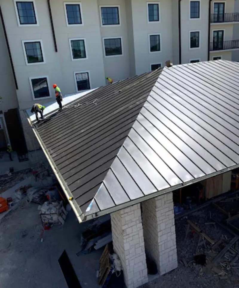 Crew installing standing seam metal roof panels on a commercial project in Hampton
